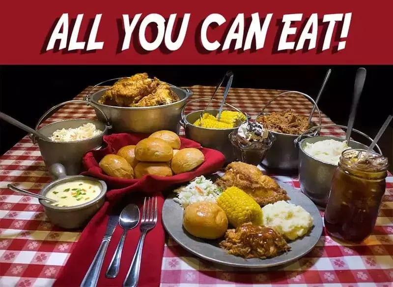 Southern homestyle feast with chicken, corn, potatoes and vegetables on a gingham table with text 'All You Can Eat'.