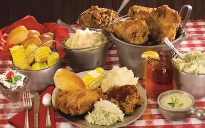 Southern feast at Hatfield & McCoy Dinner Feud with fried chicken, corn, ribs, coleslaw and honey jar on checkered table
