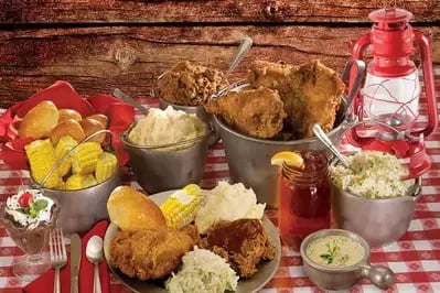 Southern feast at Hatfield & McCoy Dinner Feud with fried chicken, corn, mashed potatoes, ribs and lantern on gingham table